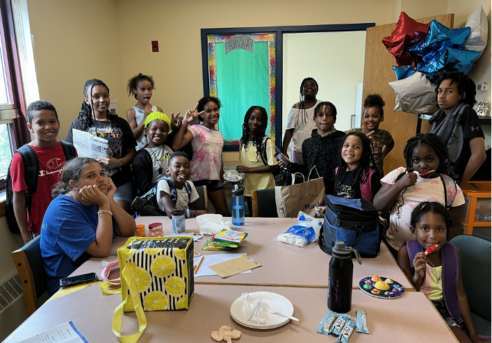 METCO SummerFun attendees enjoying themselves around a table with snacks and balloons.